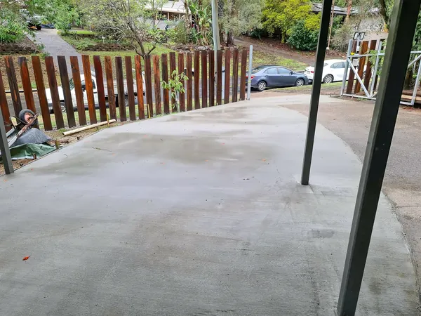 Wide poured concrete driveway with a new timber fence