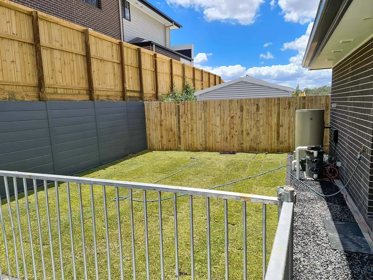 Fresh green turf laid against a new timber fence and white pool fence